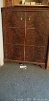 Front view of the Mahogany cabinet showing wood grain, two doors with metal pulls, and cabinet base with cut out design.