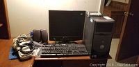 Wide shot showing Dell desktop tower, LCD monitor, wired keyboard, pair of speakers on a wooden table.