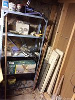 Photo showing metal shelving unit, boxed Heritage 52in ceiling fan and assorted workshop items stored on shelves.