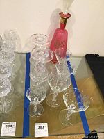 Clear antique wine glasses with Star of David on base, two glass candle holders, and pink glass decanter with Menorah design