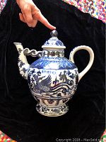 Side view of the blue and white handmade Chinese porcelain urn with lid and handle, showing detailed painting and shape.