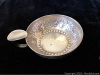 Silver plated bowl with floral and geometric embossed pattern and handle attached to side