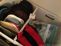 Assortment of various hats including baseball caps and fedoras in fabric box