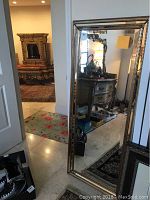 Full view of the large standing mirror positioned near a doorway showing its overall size and shape.