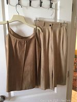 Camel soft leather one shoulder top and camel wide leg leather pants hanging on hangers