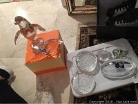 Overview of assorted glass animal figurines displayed on the floor and a tray, including seal and bird shapes, with clear and amber coloring.