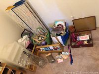 Overall view showing fabric measuring boards, plastic shelves, containers with various small craft supplies and paints.