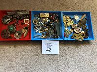 Overview of three plastic trays containing assorted vintage jewelry and metal accessories