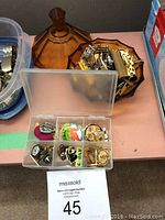 Overall lot with plastic box and amber glass dish beside it filled with cufflinks and pins