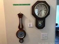 Photo showing the wooden barometer missing the thermometer alongside the plastic regulator clock with pendulum window.
