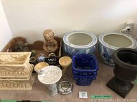Lot comprising various decorative planters and garden figurines arranged on floor and in cardboard box.