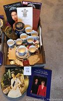 Full view of the lot showing teacups, saucers, tins, several books about British royalty