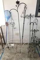 Front view of wire carriage plant holder and black wire hanging basket holders with decorative bird and flower motifs