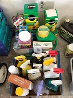 Photo showing multiple gardening products including Miracle-Gro, Jobe's fertilizer, Nurseryland Growing Food, spray bottles with colored nozzles, and various plastic bottles.