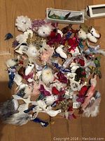 Bird ornaments laid out on floor showing variety of feathered and glittered Christmas birds in multiple colors and sizes.