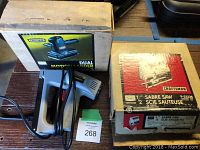 Craftsman sander and sabre saw in original boxes with staple gun partially visible.