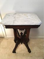 Front view of the marble top table showing the white and gray marble surface and carved wooden base.