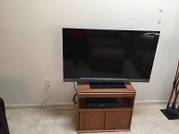 Sony flatscreen TV on wooden stand with cable box in living room setting