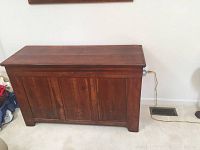Front view of vintage wooden dough chest showing paneled front and dovetail joints on sides.