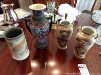 Front view of four vases placed on wooden table showing details and overall condition of each