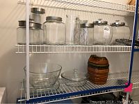 Glass kitchen storage jars and bowls on white metal shelving