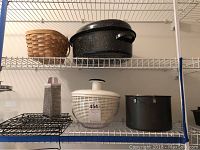 Photo of kitchen items on wire shelving: roasting pan, stock pot, salad spinner, grater, cooling racks, basket