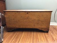 Front view of the wood chest showing worn surface and lock removal area