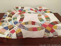 Folded view of the Double Wedding Ring pattern quilt with multi-colored floral fabric pieces on a white background.