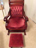 Full frontal view of the vintage red velvet upholstered rocker and matching foot stool on carpet.