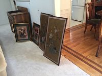 Four framed flower prints lined up on carpet - two Japanese floral prints and two Barbara Mock prints.