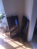 Two framed Japanese jade art panels leaning against a wall in a sunlit corner. Frames show marks, art depicts jade motifs and kanji characters.