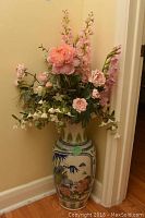 Full view of the faux flower arrangement in the ceramic Asian motif vase positioned in a corner against the walls.
