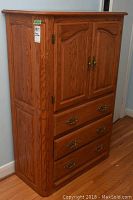Full front view of Shermag oak wood armoire showing upper double cabinet doors and three lower drawers with metal pulls.