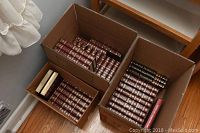 Three cardboard boxes filled with multiple hardcover volumes of Funk and Wagnalls encyclopedias and yearbooks.