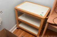 Full view of the multi-tier wood and white laminate utility cart showing shelves and wheels.