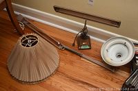 The full extension lamp laid out with its base, arm, fluorescent light fixture, and two lamp shades on a hardwood floor.