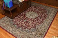 Area rug showing full design, central medallion, and border on hardwood floor with nearby furniture.