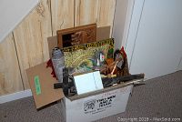 Box with religious wood carvings, small statues and some framed artwork leaning against the wall