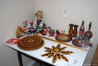 Full view of the collection including the doll, wooden platters, carved wall hanging, wooden and painted vases, and small decorative items