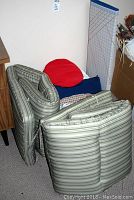 Four striped outdoor chair cushions stacked with decorative pillows behind them.