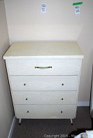 Front view of vintage dresser showing 4 drawers with metal handles and knobs, light wood grain finish.