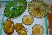Photo showing an assortment of amber glass serving pieces and a green carnival glass footed bowl.