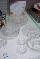 Multiple lead crystal serving bowls and ashtrays displayed on a table showing detailed cut patterns and shapes.