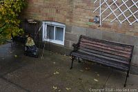 Bench and metal plant shelf visible with tomato cages and mulch bag nearby on concrete patio.