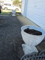 Two white urn-style resin planters on driveway