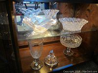 Top shelf view showing large wavy-edged fruit bowl and two pedestal cut crystal bowls.