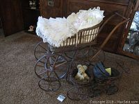 Photo showing entire wicker stroller with porcelain doll sitting inside, small stroller and small bicycle with bear on the carpeted floor.