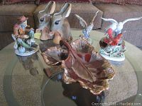 Glass table top view showing all pottery and figurine items including fisherman, donkey planters, leaf candy dish, and bird figurines.