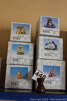 Photo of six stacked Fitz and Floyd Charming Tails figurine boxes showcasing titles and item numbers.