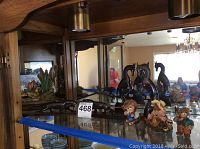 Display cabinet shelf showing Lenox frog sculpture and acrylic animal figurines of tigers and horses.